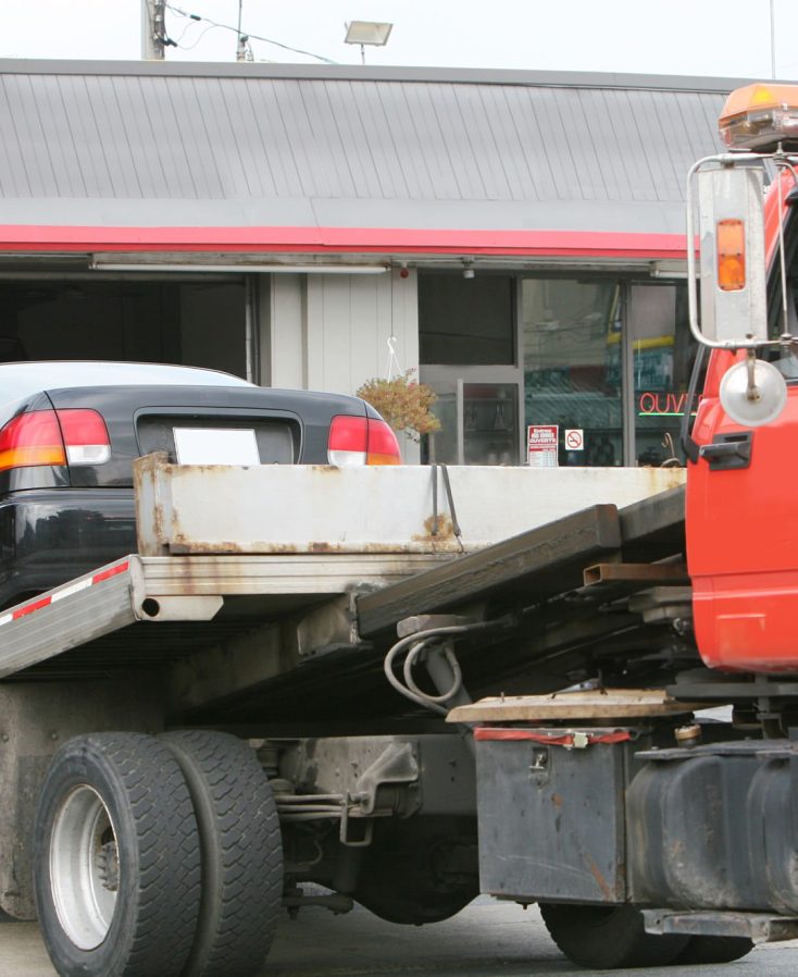 Tow truck bringing a car at the car repair shop.